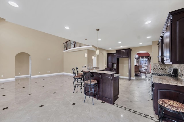 kitchen featuring electric stove, hanging light fixtures, light tile patterned floors, light stone counters, and dark brown cabinetry