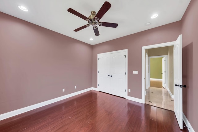 unfurnished bedroom with ceiling fan, dark wood-type flooring, and a closet