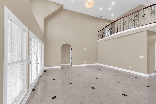 unfurnished living room featuring light tile patterned flooring and a high ceiling