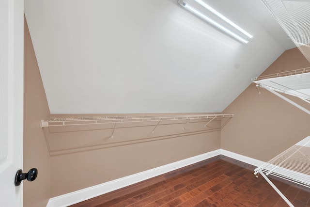 spacious closet with dark wood-type flooring and vaulted ceiling