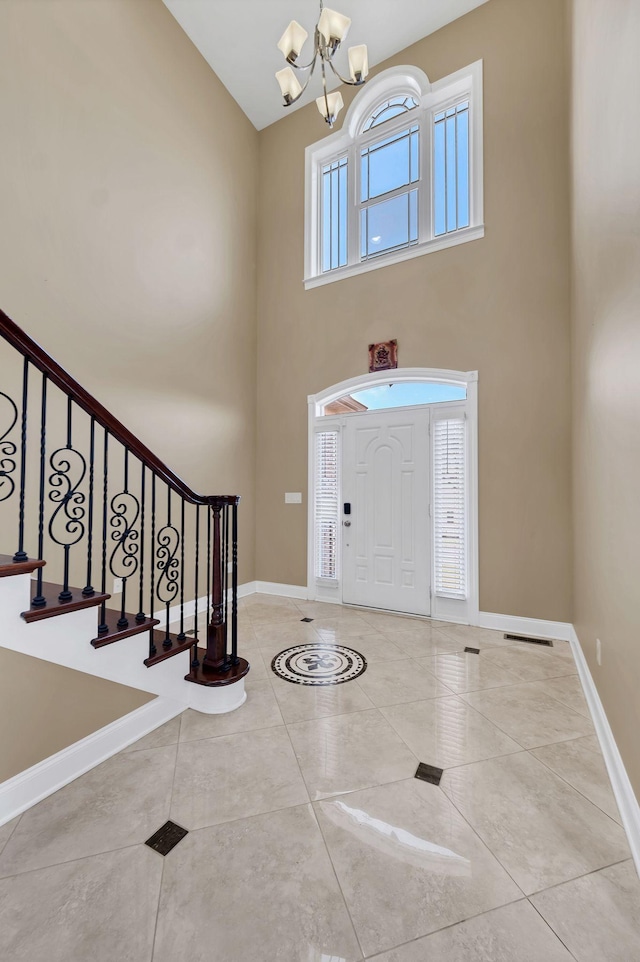 tiled entryway featuring a chandelier and a high ceiling