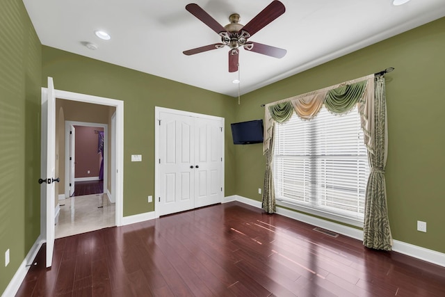 unfurnished bedroom with ceiling fan, dark hardwood / wood-style floors, and a closet