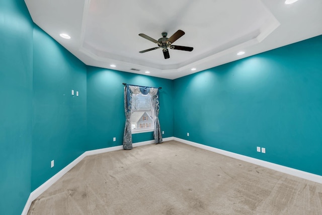 spare room with carpet floors, a tray ceiling, and ceiling fan