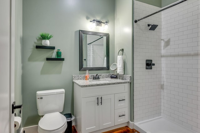 bathroom featuring toilet, vanity, and tiled shower