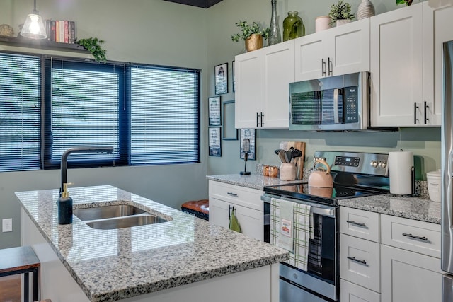 kitchen with a center island with sink, decorative light fixtures, white cabinetry, and stainless steel appliances