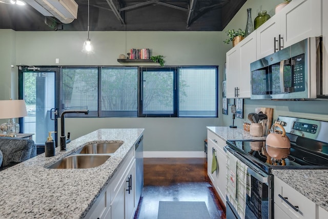 kitchen featuring white cabinetry, sink, stainless steel appliances, light stone counters, and decorative light fixtures