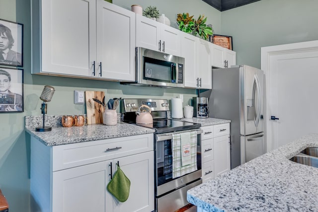 kitchen with light stone counters, white cabinets, and appliances with stainless steel finishes