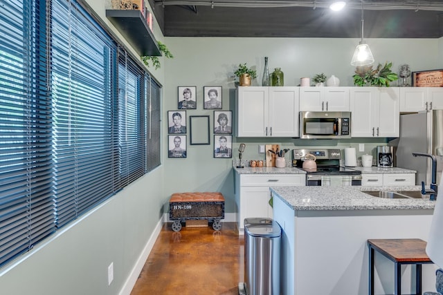 kitchen featuring light stone countertops, white cabinets, hanging light fixtures, and appliances with stainless steel finishes