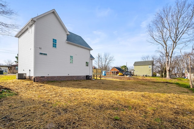 view of side of home featuring cooling unit and a yard