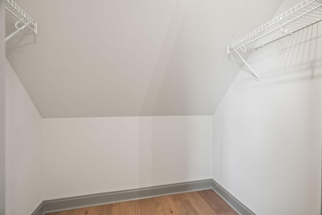 walk in closet with wood-type flooring and vaulted ceiling