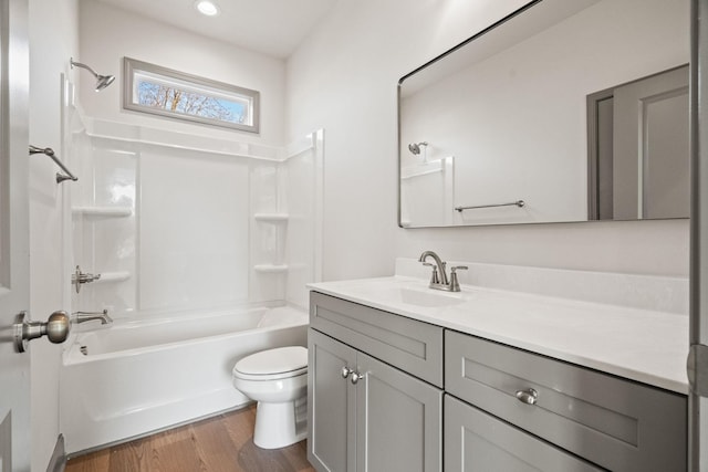 full bathroom with hardwood / wood-style flooring, vanity,  shower combination, and toilet