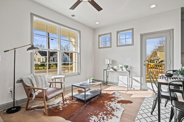 living area featuring ceiling fan, light wood-type flooring, and a wealth of natural light