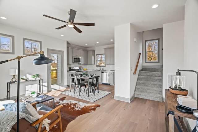 living room featuring ceiling fan, plenty of natural light, light wood-type flooring, and sink