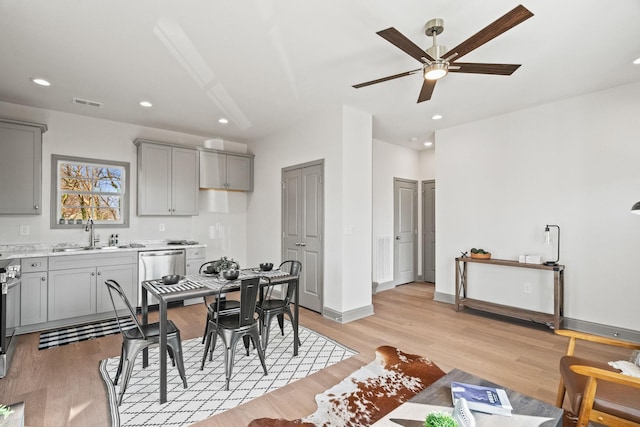 dining room featuring ceiling fan, sink, and light hardwood / wood-style floors