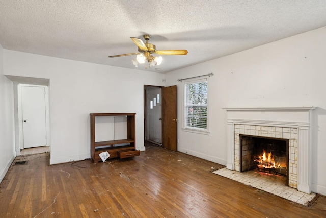 unfurnished living room featuring hardwood / wood-style floors, a textured ceiling, a fireplace, and ceiling fan