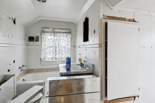 bathroom featuring vaulted ceiling and a bath