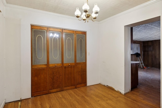 interior space with ornamental molding, wood-type flooring, and a notable chandelier