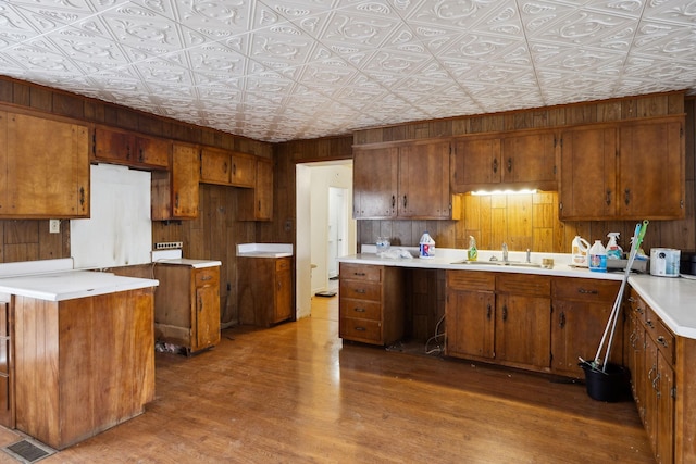 kitchen with a kitchen island, sink, hardwood / wood-style floors, and wood walls