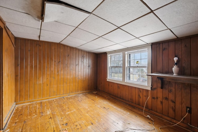 interior space featuring a paneled ceiling, wood-type flooring, and wooden walls