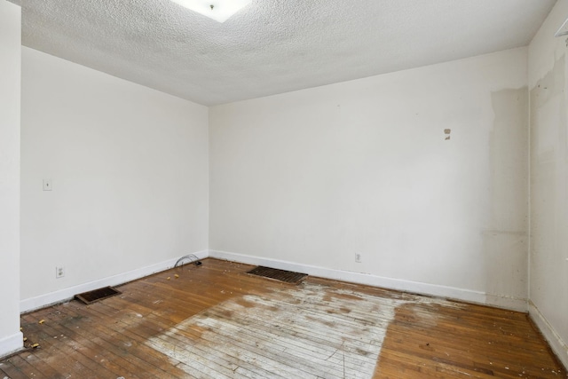 spare room featuring hardwood / wood-style floors and a textured ceiling