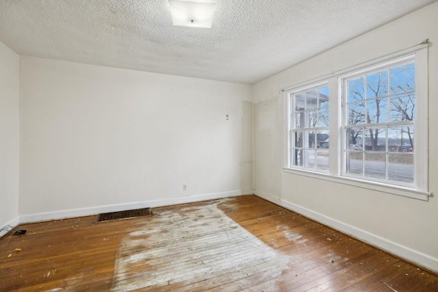 empty room featuring wood-type flooring and a textured ceiling