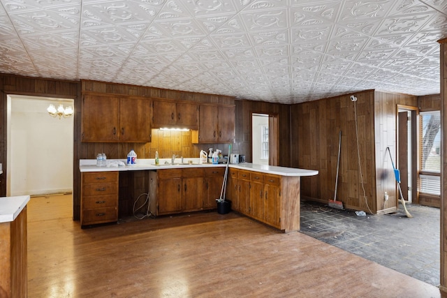 kitchen with dark hardwood / wood-style floors, kitchen peninsula, sink, and wood walls