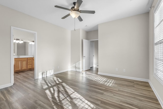 unfurnished bedroom with ensuite bathroom, sink, ceiling fan, and dark wood-type flooring