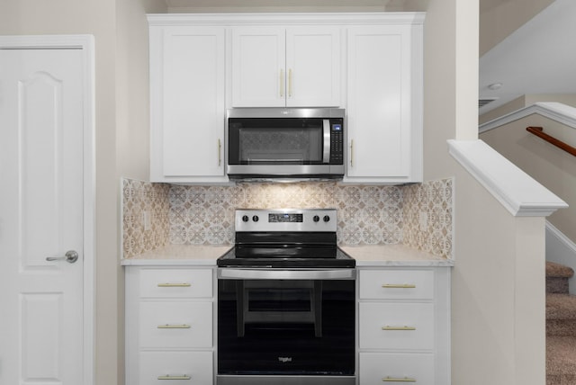 kitchen with backsplash, white cabinetry, and appliances with stainless steel finishes