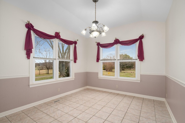 tiled spare room with a notable chandelier