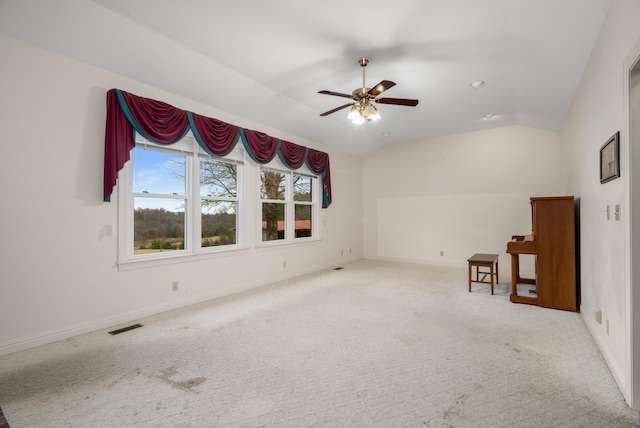 carpeted spare room featuring vaulted ceiling and ceiling fan