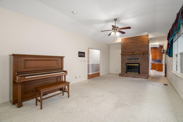 carpeted living room featuring vaulted ceiling, a brick fireplace, and ceiling fan