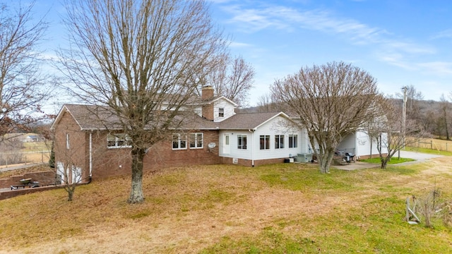 rear view of house featuring a lawn and central AC unit