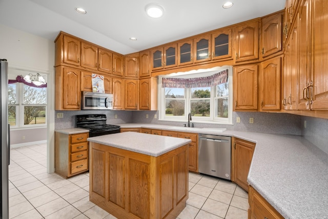 kitchen with appliances with stainless steel finishes, tasteful backsplash, sink, a center island, and light tile patterned flooring