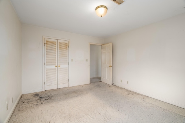 unfurnished bedroom featuring light colored carpet and a closet