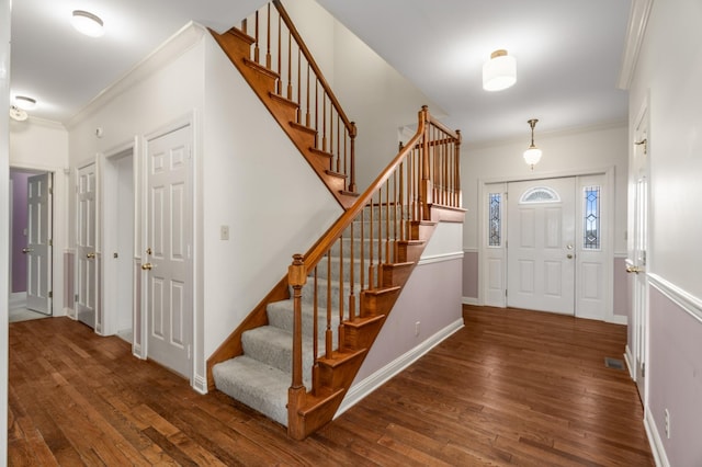 foyer entrance with crown molding and dark hardwood / wood-style floors