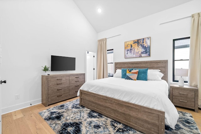 bedroom featuring high vaulted ceiling and light hardwood / wood-style floors