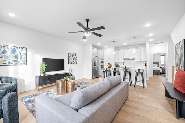 living room with ceiling fan and light wood-type flooring