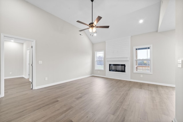 unfurnished living room with a large fireplace, light wood-type flooring, and a healthy amount of sunlight