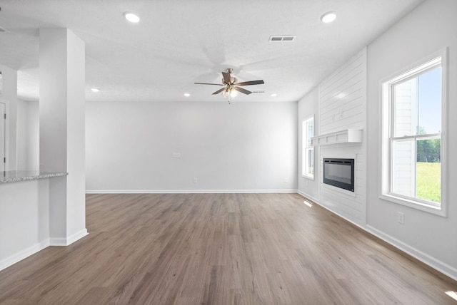 unfurnished living room with hardwood / wood-style floors, ceiling fan, a large fireplace, and a textured ceiling