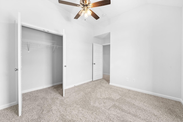 unfurnished bedroom featuring ceiling fan, a closet, light colored carpet, and vaulted ceiling