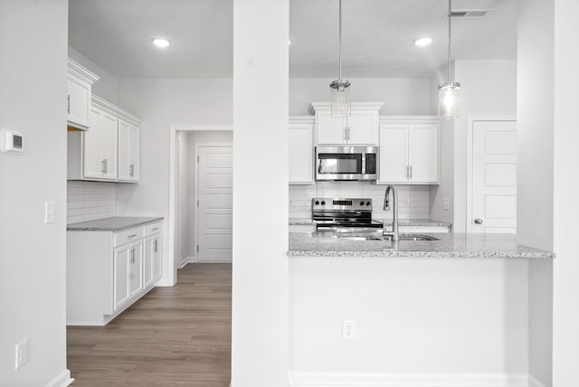 kitchen with pendant lighting, backsplash, white cabinets, sink, and stainless steel appliances