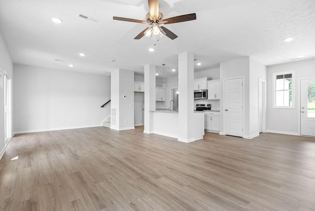 unfurnished living room featuring ceiling fan, sink, and light hardwood / wood-style floors