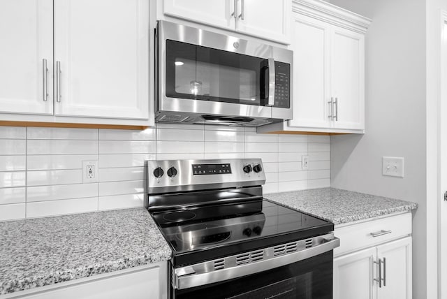 kitchen featuring decorative backsplash, light stone countertops, white cabinetry, and appliances with stainless steel finishes