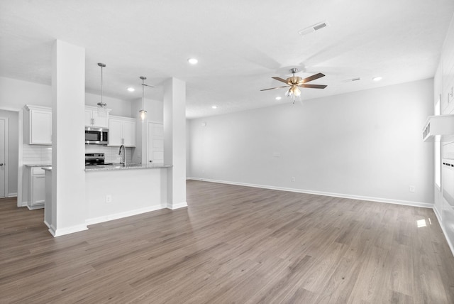 unfurnished living room featuring hardwood / wood-style flooring, ceiling fan, and sink