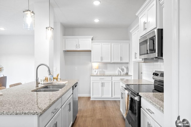 kitchen with pendant lighting, white cabinets, sink, decorative backsplash, and stainless steel appliances