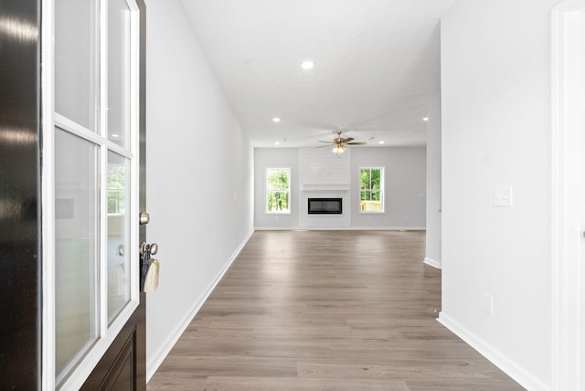 unfurnished living room with a fireplace, light wood-type flooring, and ceiling fan