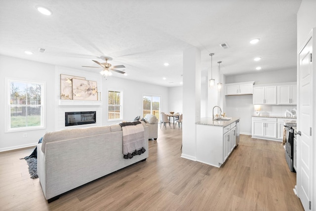 kitchen featuring sink, tasteful backsplash, pendant lighting, stainless steel electric range, and white cabinets