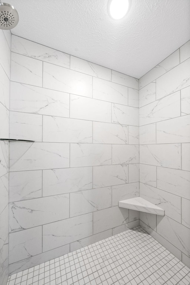 bathroom with a tile shower and a textured ceiling