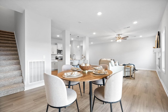 dining area with light hardwood / wood-style floors, ceiling fan, and sink