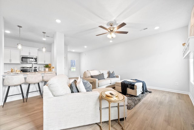 living room featuring light hardwood / wood-style flooring and ceiling fan